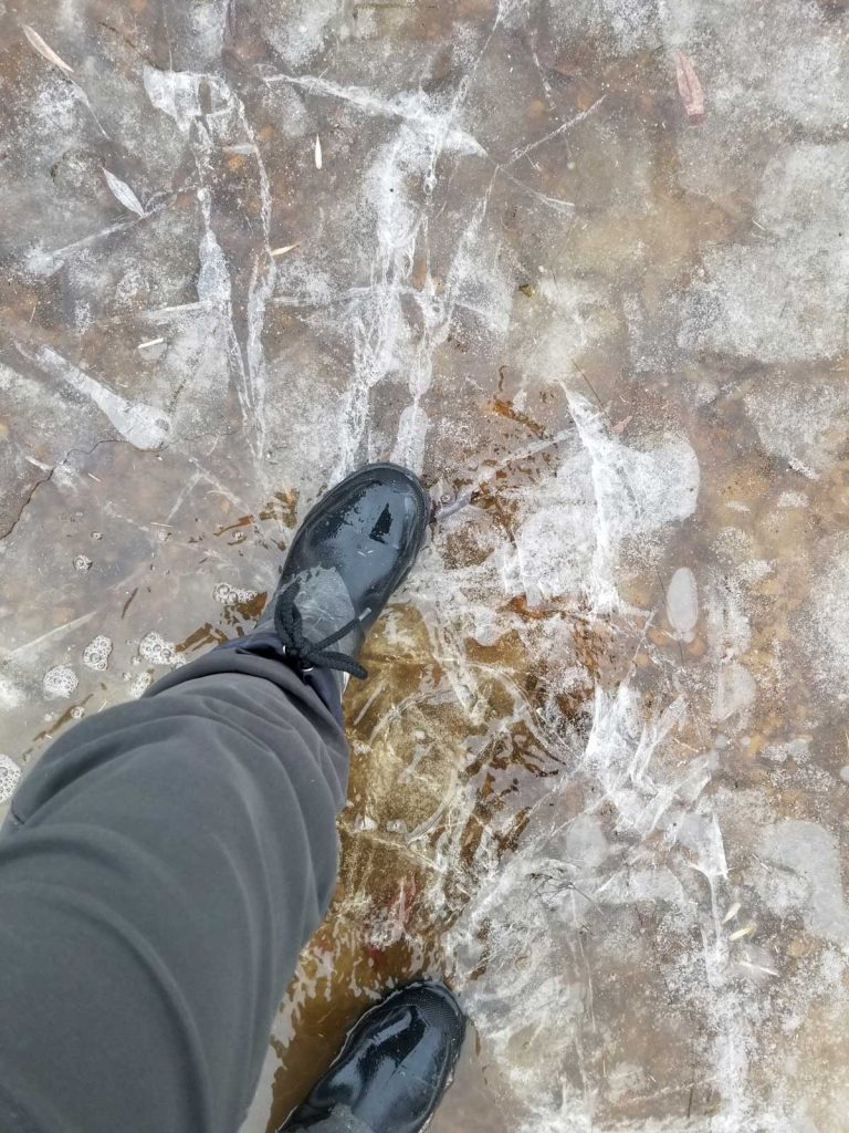 This image shows a boot pushing down onto ice.