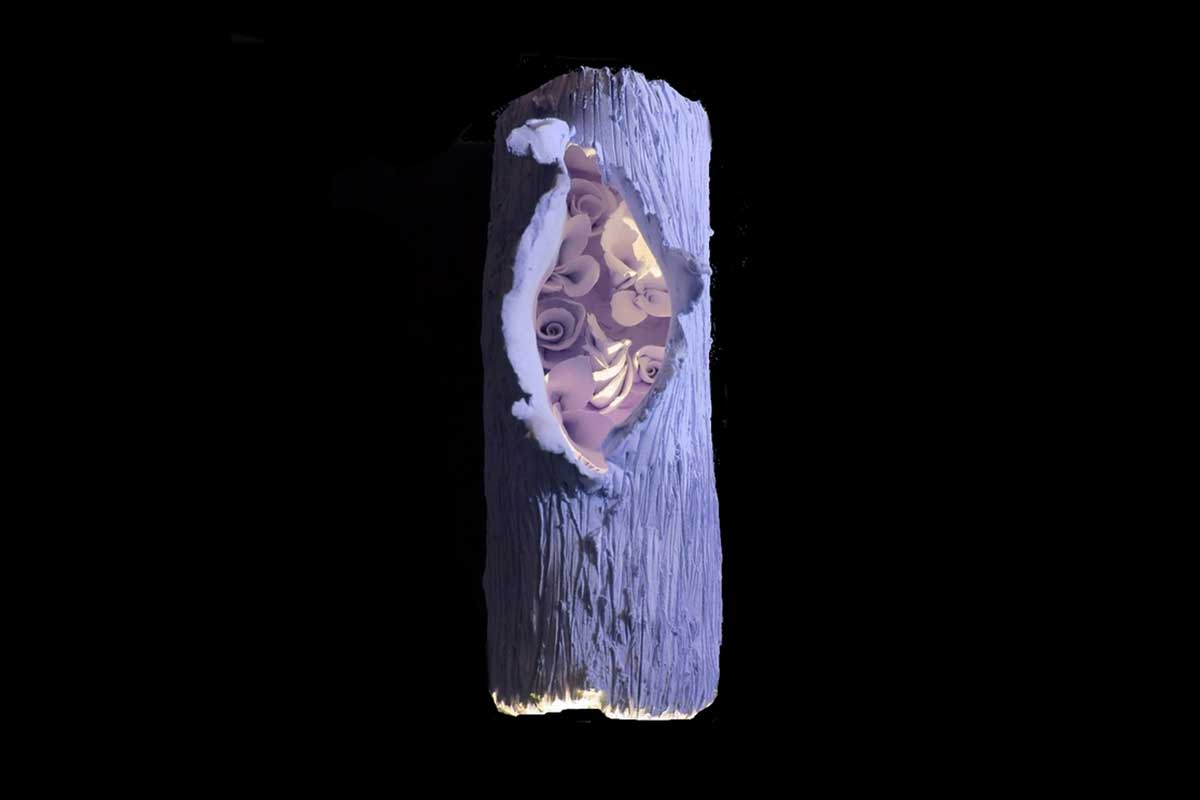 A ceramic tree log, with an opening in the center to reveal glowing flora within