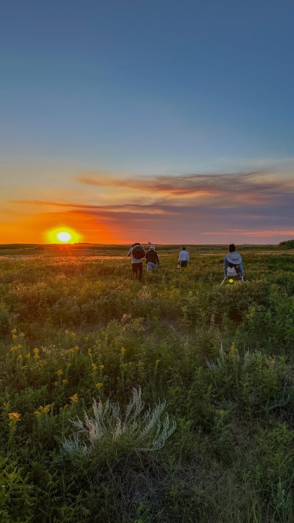Sunset over the grassland at Mattheis Research Ranch, Alberta, Canada with researchers walking back after a long day of fieldwork.