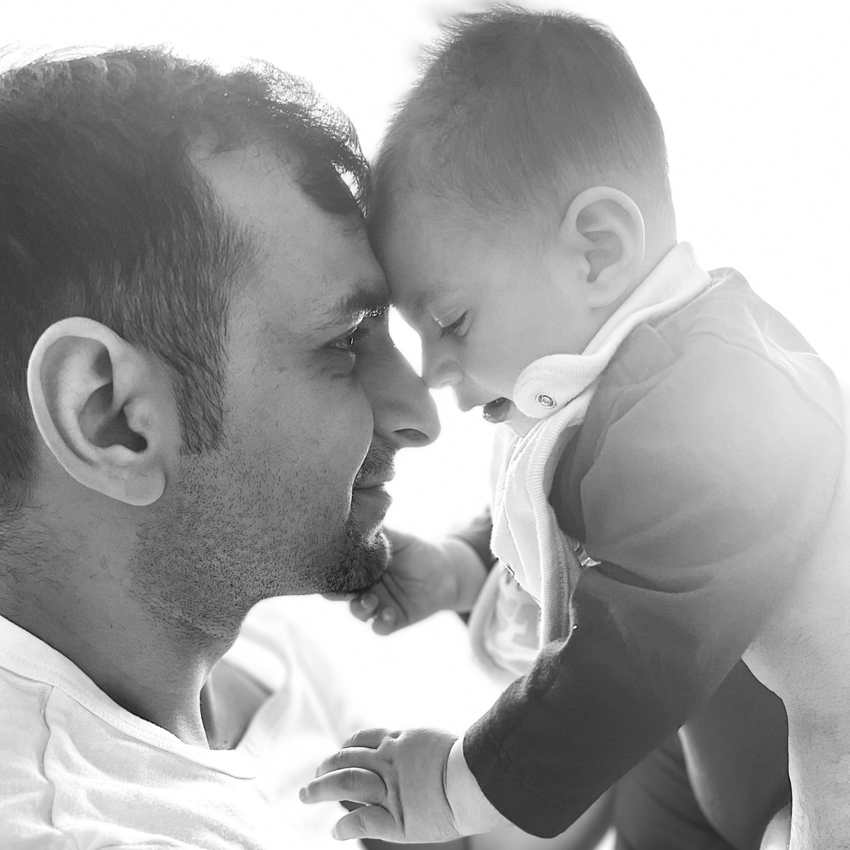 A man and a baby meet forehead to forehead
