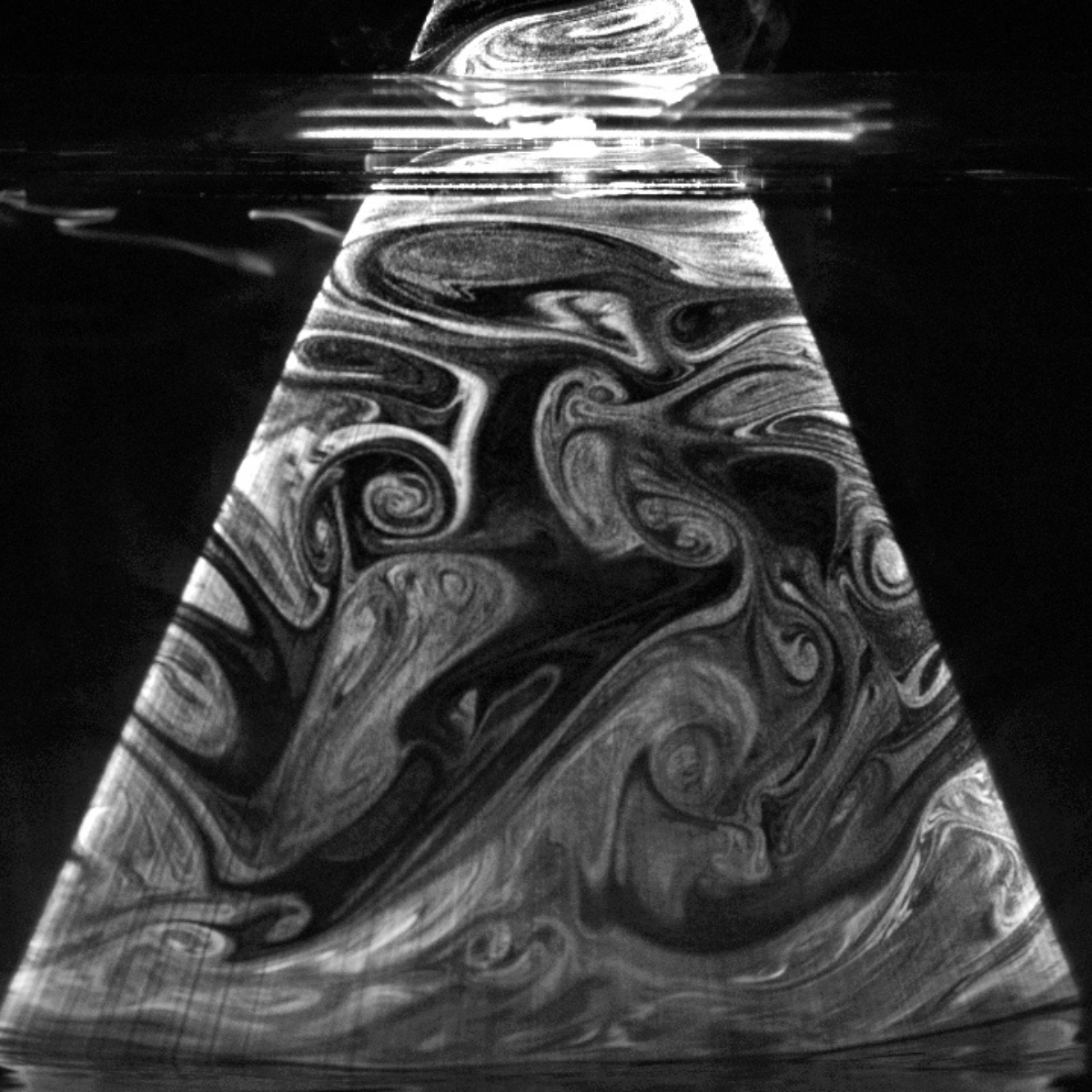 Grayscale visualization of turbulent airflow patterns using smoke structures within a sewer pipe cross-section.