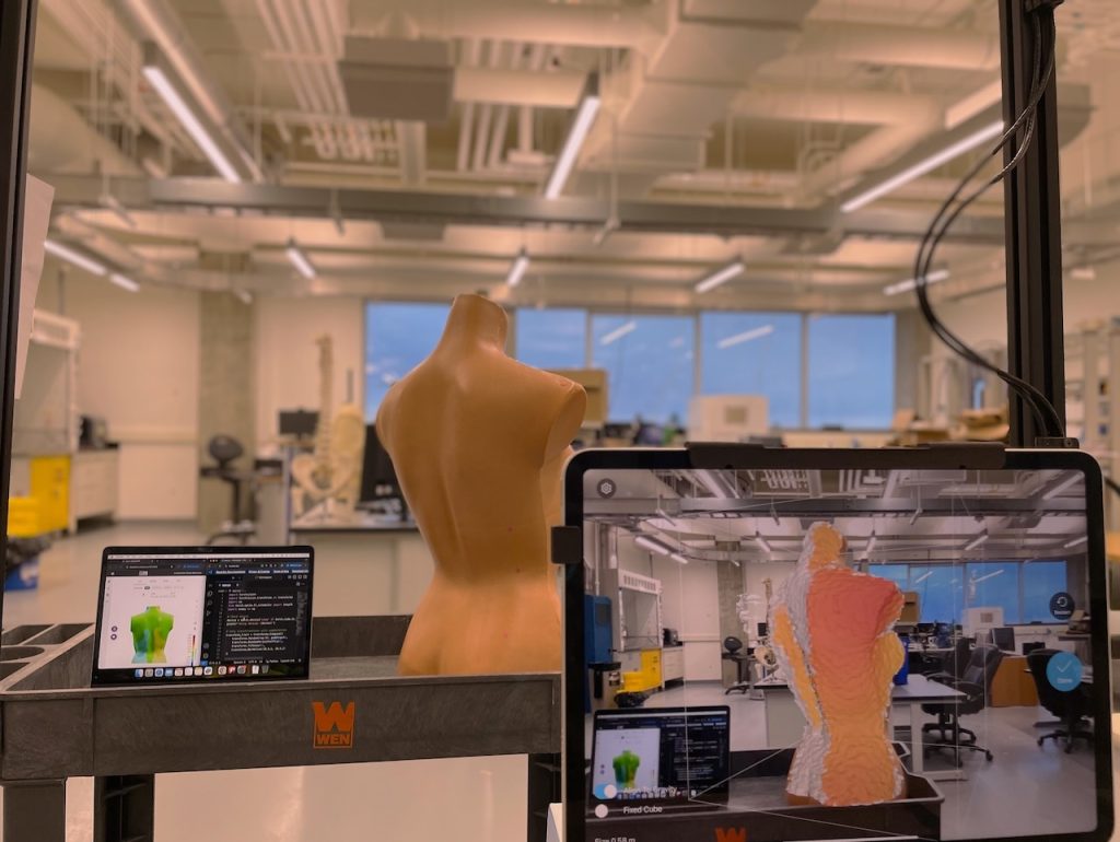 A mannequin mid-scan using iPad and Structure Sensor, with spine depth deviations shown on BackSCNR website and VS Code.