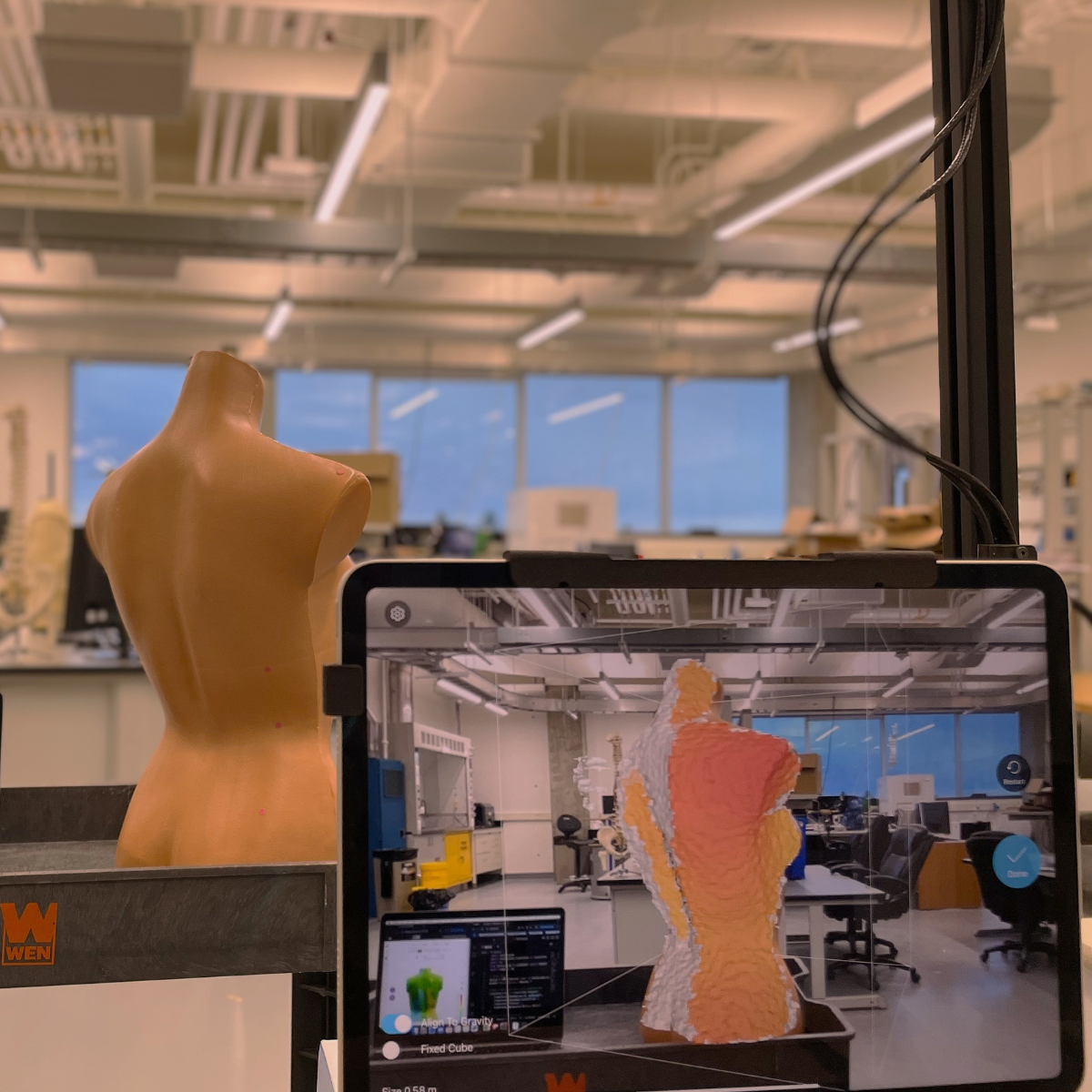 A mannequin mid-scan using iPad and Structure Sensor, with spine depth deviations shown on BackSCNR website and VS Code.