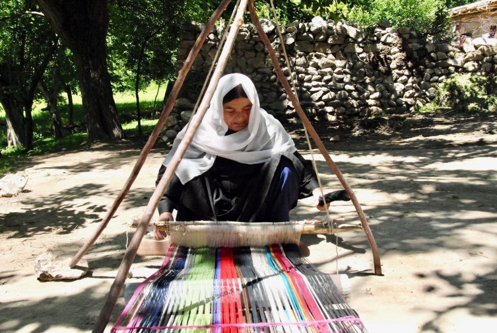 A woman weaving a shawl on a traditional loom, representing cultural heritage and women’s economic empowerment.