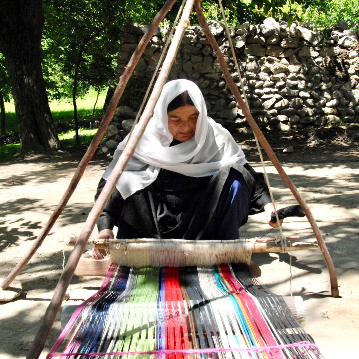 A woman weaving a shawl on a traditional loom, representing cultural heritage and women’s economic empowerment.