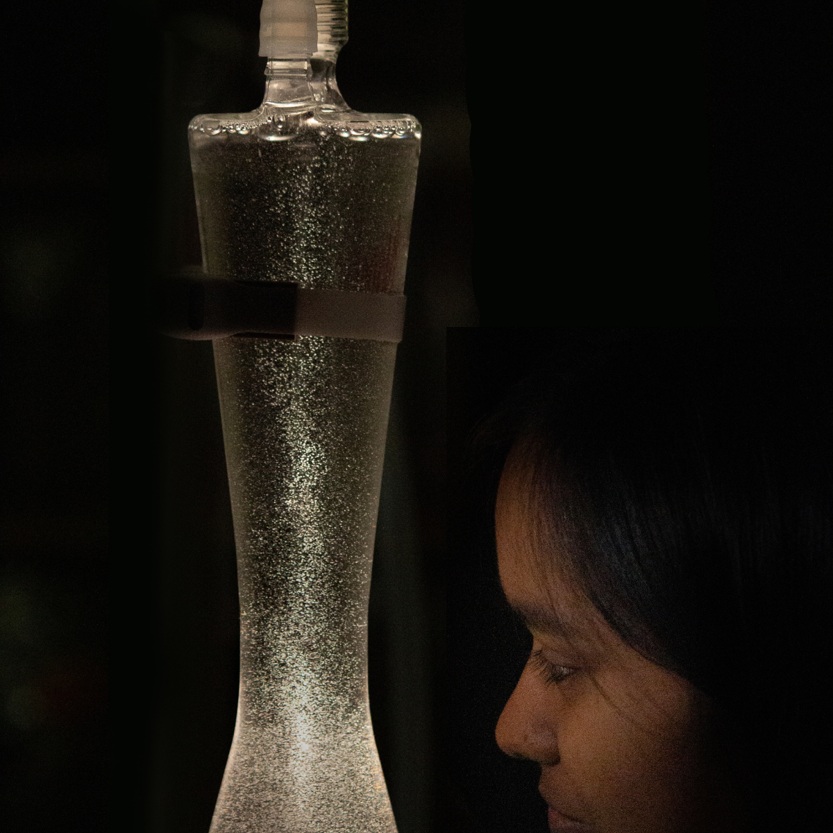 A researcher gazes at a shimmering flow chamber filled with nanobubbles suspended in liquid.