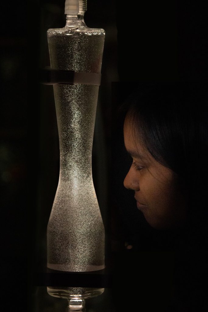 A researcher gazes at a shimmering flow chamber filled with nanobubbles suspended in liquid.