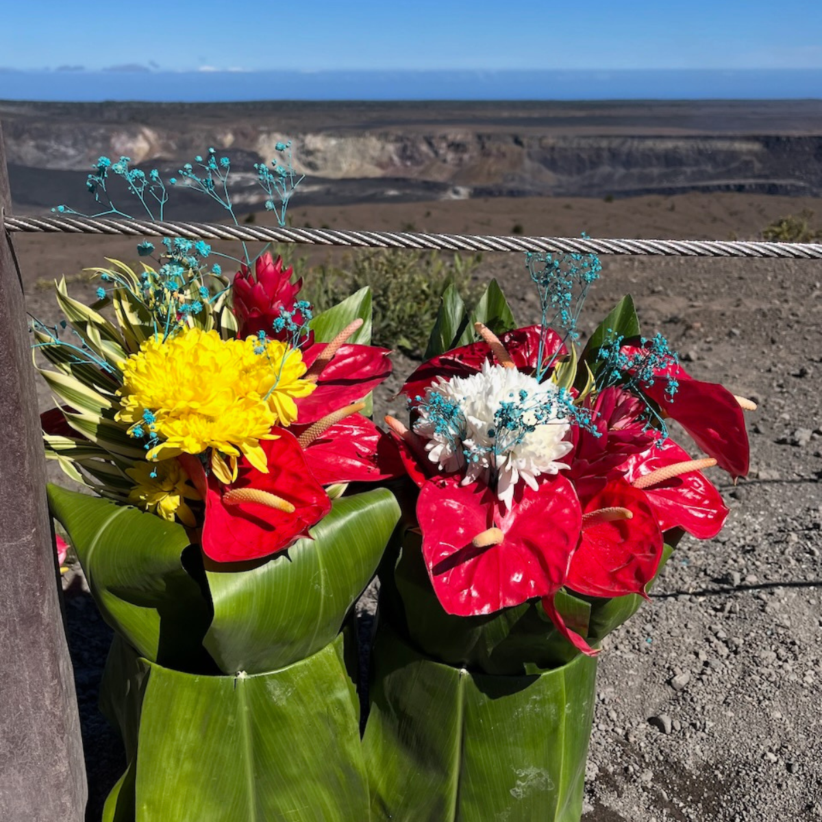 An offering of Native Hawaiian flowers wrapped in ti leaves placed on the ground near the rim of a volcanic caldera.