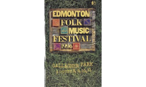 A wooden sign with the text 'Edmonton Folk Music Festival 1996' lays upon green grass.
