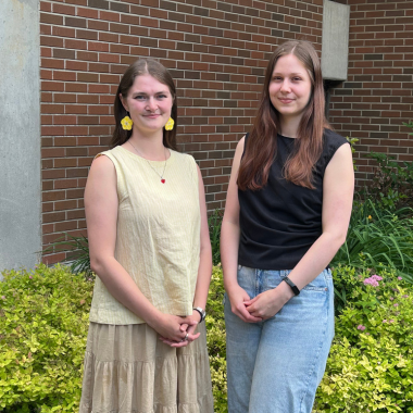 Abigail Deck holds books in her arms in the library stacks.